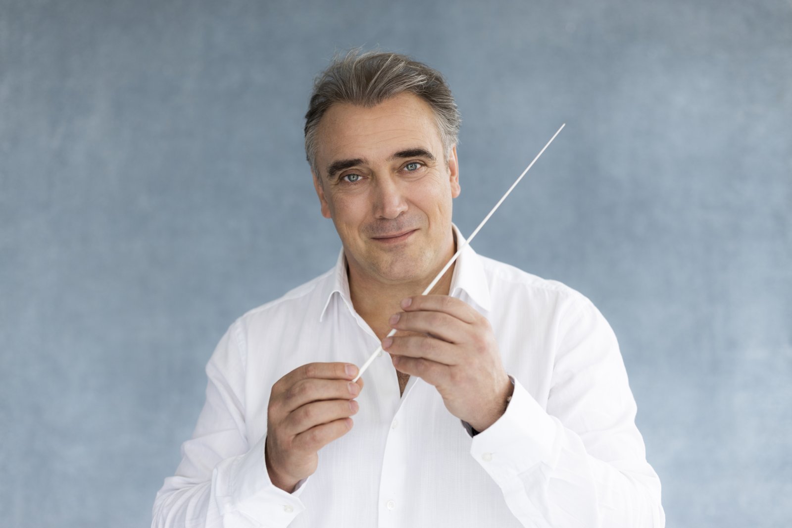 Portrait of Jaime Martín in a white shirt holding a baton